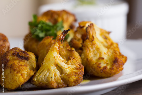 Delicious pork meat and fried cauliflowers as a side dish, served with tartar sauce on a wooden table. Close up.