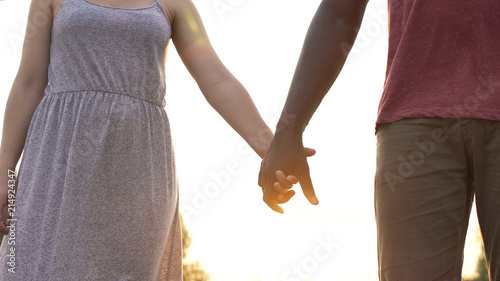 Boyfriend and girlfriend firmly clasp hands on sunset background, together © motortion
