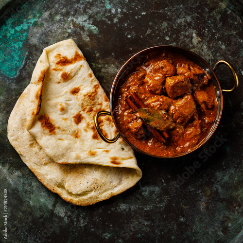 Chicken tikka masala spicy curry meat food and naan bread on dark background close-up