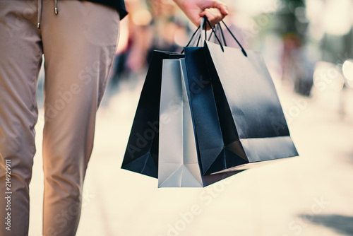 Close up of woman`s hand holding shopping bags while walking on the street. photo