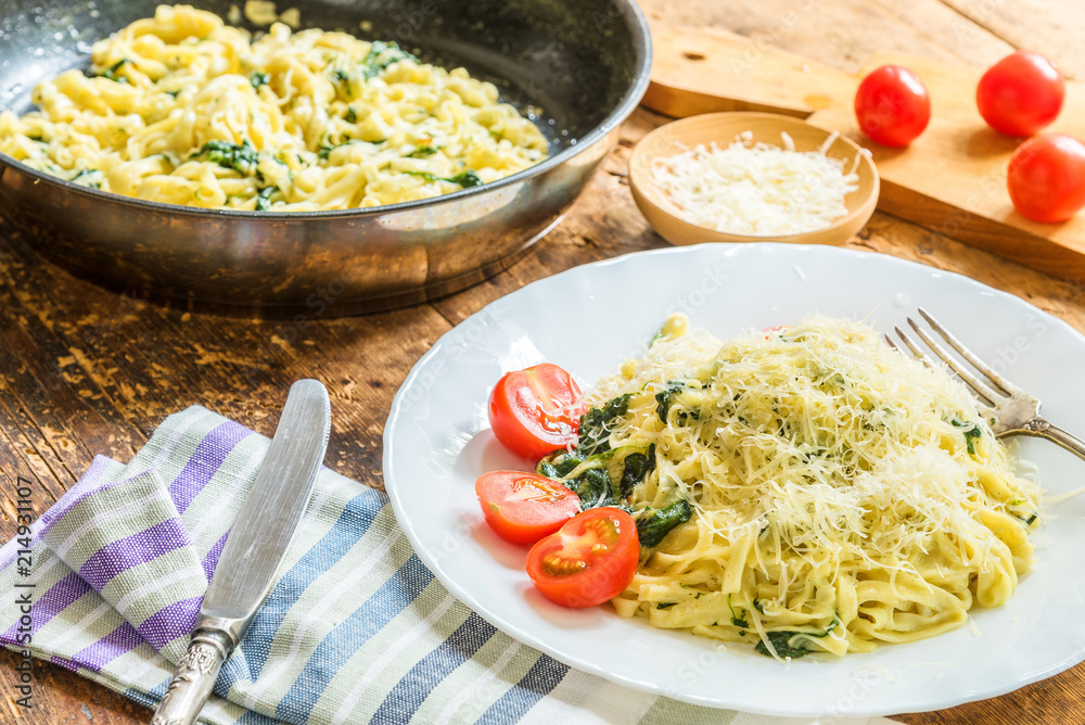 Delicious vegetarian dish - pasta fettuccine with spinach and cherry tomatoes on a rustic table Delicious vegetarian dish - pasta fettuccine with spinach and cherry tomatoes on a rustic table