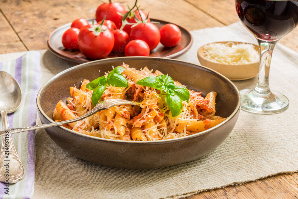Pasta All'Arrabbiata - a traditional Italian dish with parmesan cheese and red wine on a rustic background Pasta All'Arrabbiata - a traditional Italian dish with parmesan cheese and red wine on a rustic background