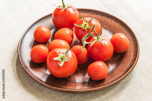 Fresh tomatoes in a clay dish on a rustic linen napkin
