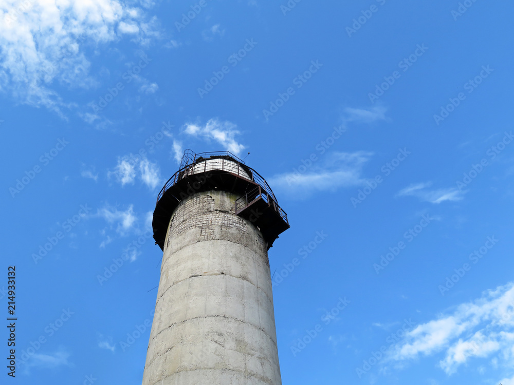 Old lighthouse tower against blue sky and white clouds, view from below Old lighthouse tower against blue sky and white clouds, view from below