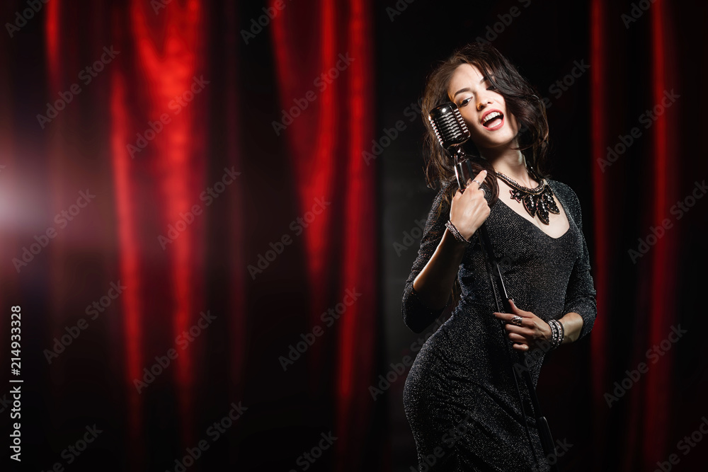 Beautiful girl in black dress singing in the microphone in the concert hall Beautiful girl in black dress singing in the microphone in the concert hall