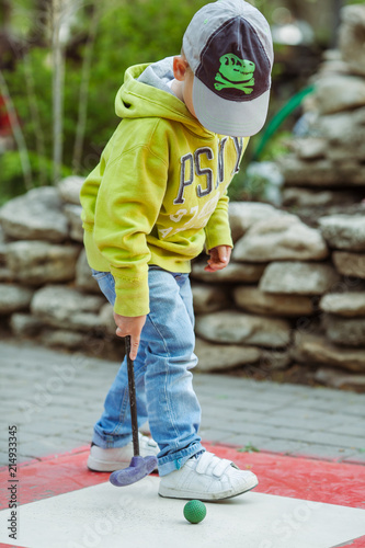 young boy playing miniature golf