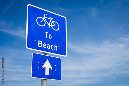 Simple blue bike lane sign indicating the direction to the beach