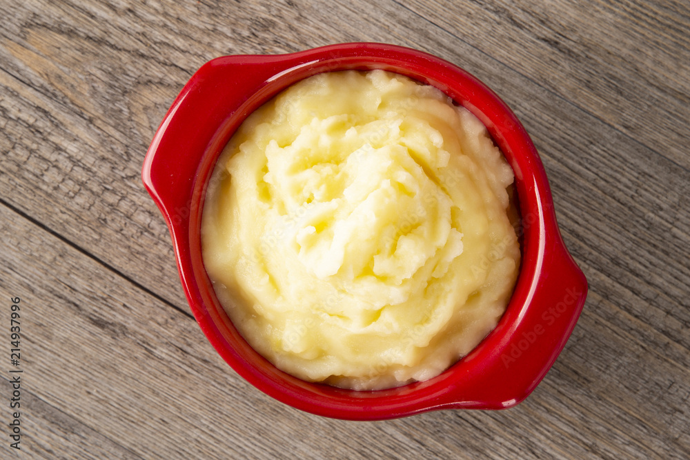 Puree from potatoes in a red saucepan. Wooden background. Top Vieux. Macro. Puree from potatoes in a red saucepan. Wooden background. Top Vieux. Macro.