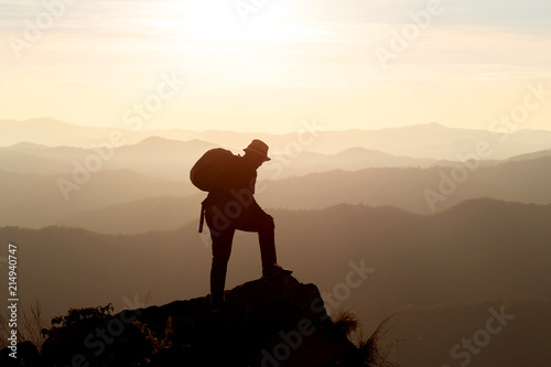 Silhouette of man hold up hands on the peak of mountain,success concept