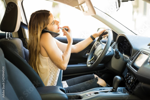 Careless woman putting on makeup and taking a phone call while driving