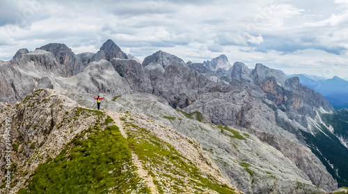 Hiker on the ridge of Dolomites Mountains in Alps, Italy. Via ferrata trail. Peole on the rocky mountains path. Travel in Dolomites. Adventure in the mountains. Mountain climber on an exposed ledge