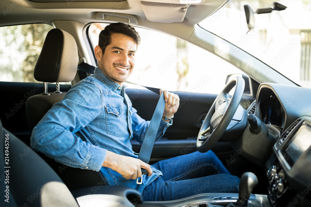 Man sitting in car seat fastening seat belt