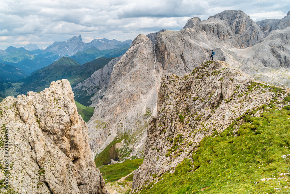 Hiker on the ridge of Dolomites Mountains in Alps, Italy. Via ferrata trail. Peole on the rocky mountains path. Travel in Dolomites. Adventure in the mountains. Mountain climber on an exposed ledge