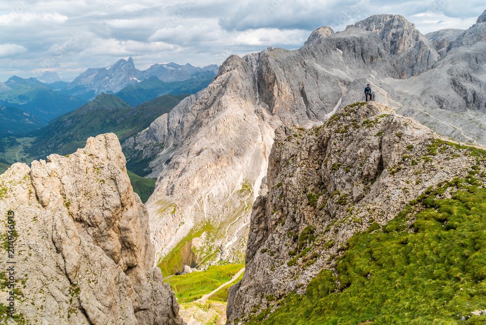 Hiker on the ridge of Dolomites Mountains in Alps, Italy. Via ferrata trail. Peole on the rocky mountains path. Travel in Dolomites. Adventure in the mountains. Mountain climber on an exposed ledge
