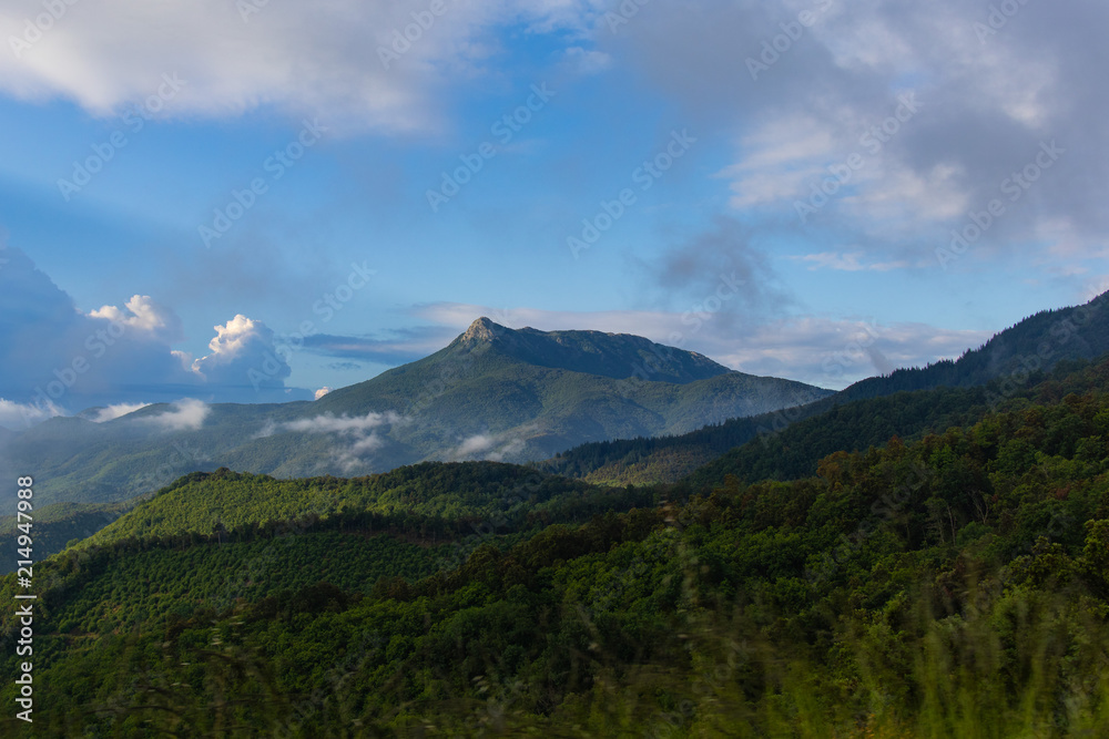 Beautiful green mountain peak landscape on a blue sky with some clouds