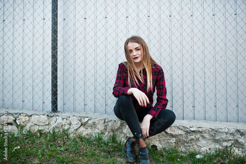 Young hipster girl in checkered shirt posed outdoor.