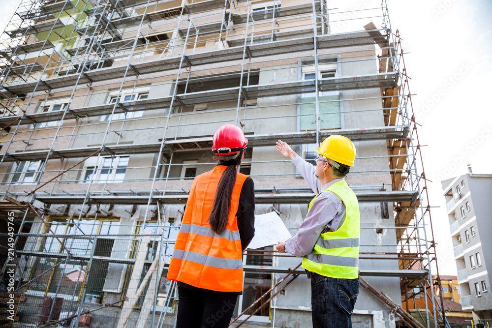 Engineers and worker discuss front of building Engineers and worker discuss front of building