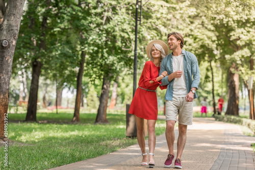 happy girlfriend and boyfriend walking together in park