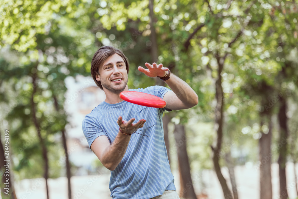 handsome man catching frisbee disk in park handsome man catching frisbee disk in park