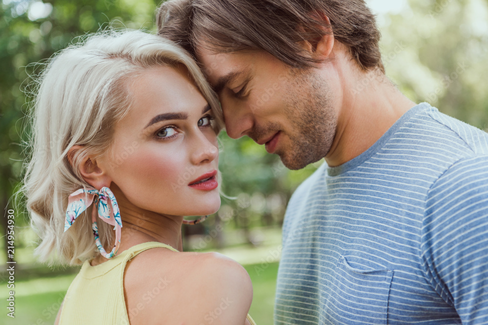 affectionate couple touching with heads in park