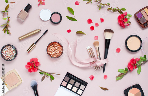 Various cosmetic products for make-up with red flowers on a pink background. Makeup Accessories Top view Flat Lay. Powder Rouge Eyeshadow Corrector Brushes Mascara