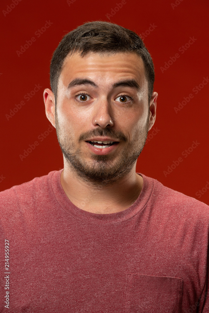 The young attractive man looking suprised isolated on red The young attractive man looking suprised isolated on red