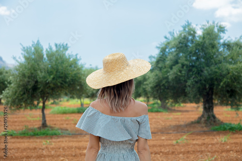 Young redhead girl wearing in dress and hat have a rest in greek olive garden in Heraklion, Crete, Greece