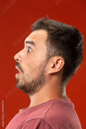 The young attractive man looking suprised isolated on red