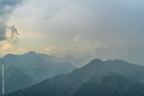 Italian Dolomites Landscape. Light after rain in Dolomites. Rocky peaks in the background surrounded by rain clouds. Mountain valley with layers of forest and mountains. Beautiful light in Alps. Italy