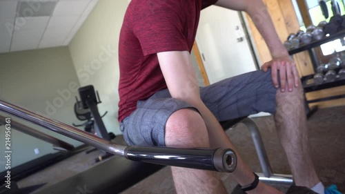 a shot of a young man curling weights on a bench in a gym. photo