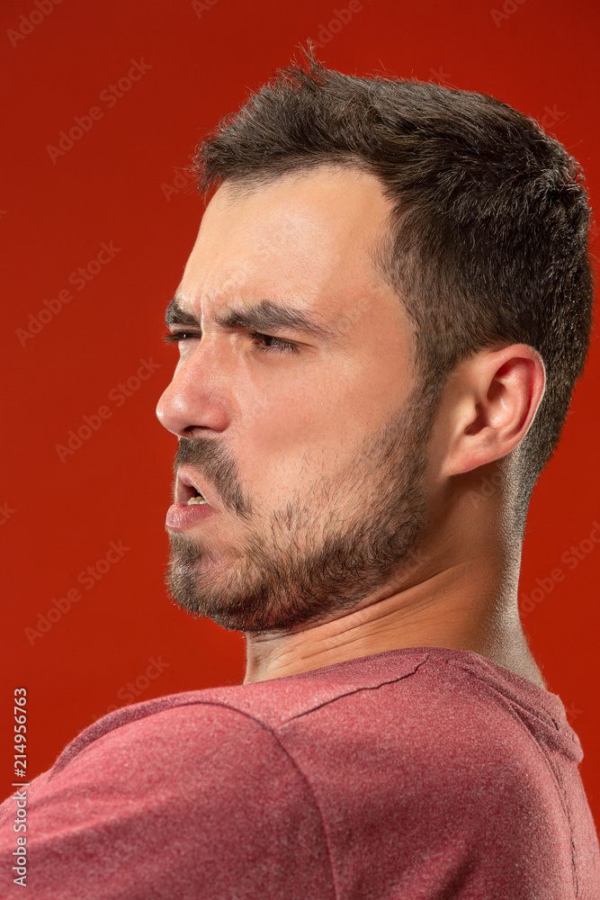 The young emotional angry man screaming on red studio background The young emotional angry man screaming on red studio background