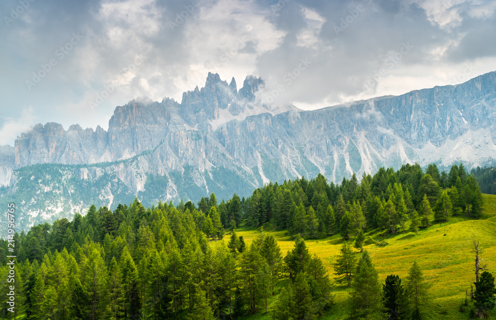 Landscape of Dolomites with green meadows, blue sky, white clouds and rocky mountains. Italian Dolomites landscape. Beauty of nature concept background. The valley below. Evening panoramic view. 