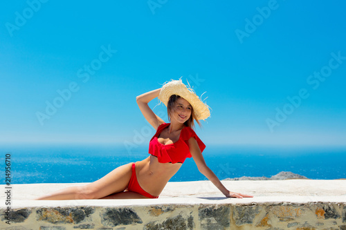 Young girl in bikini on terrace with blue sea and sky on background. Crete, Greece