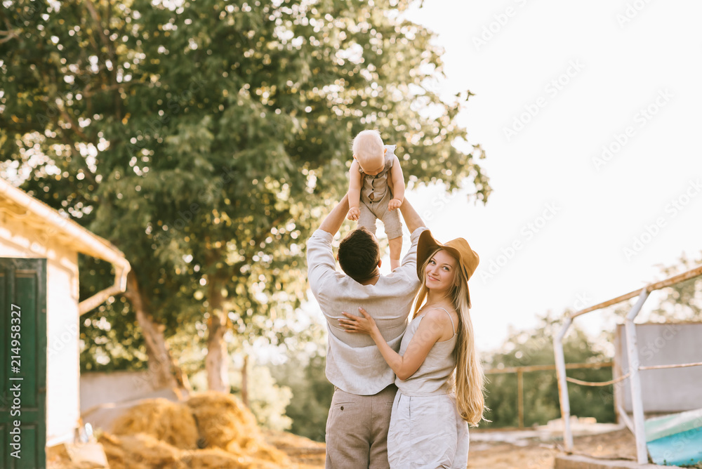 back view of woman standing near husband with son on hands at countryside back view of woman standing near husband with son on hands at countryside