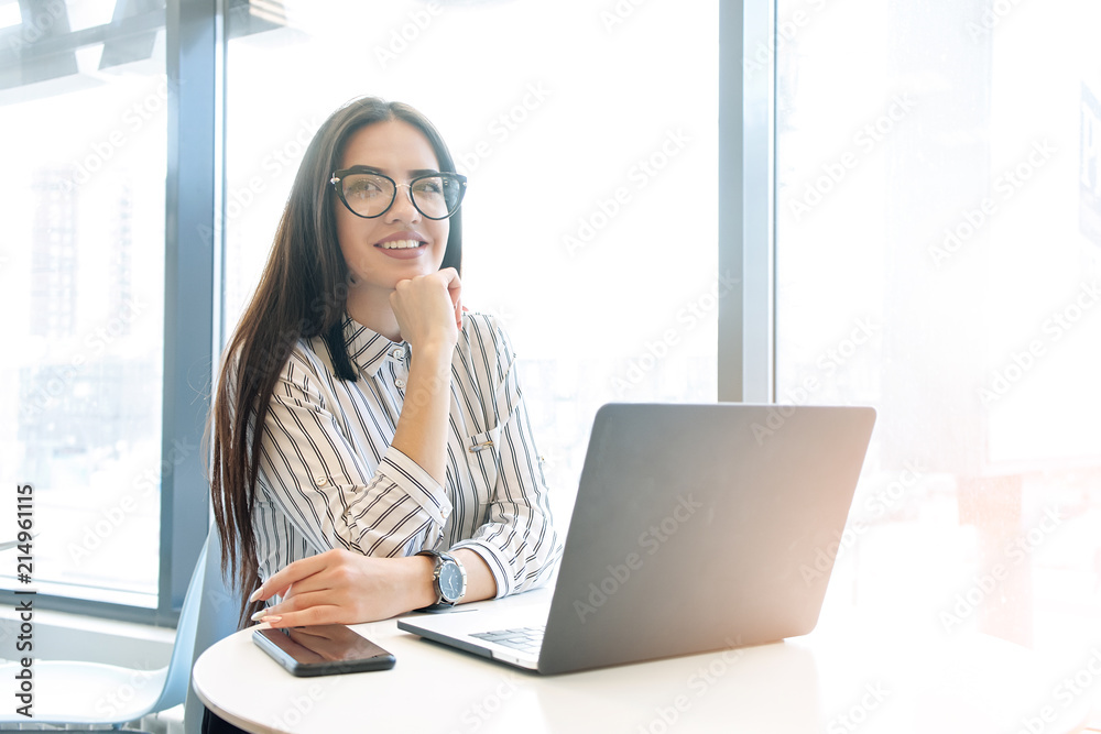 Beautiful business lady is looking at camera and smiling while working in office Beautiful business lady is looking at camera and smiling while working in office