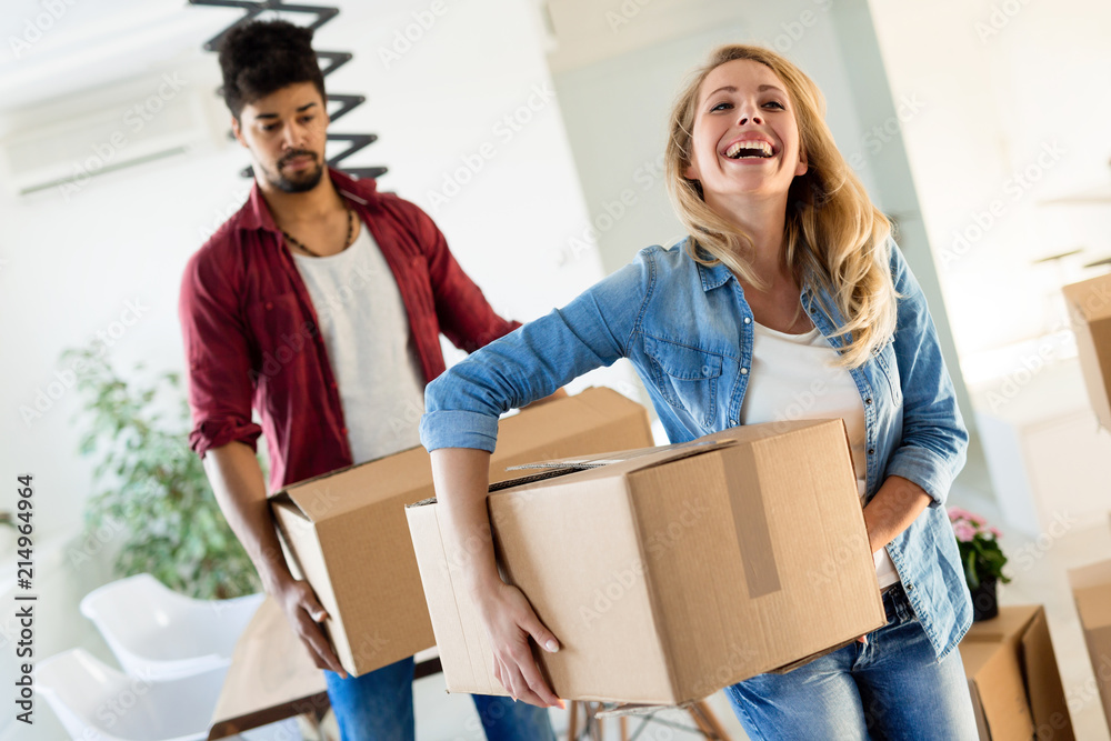 Young couple unpacking cardboard boxes at new home moving in concept Young couple unpacking cardboard boxes at new home moving in concept