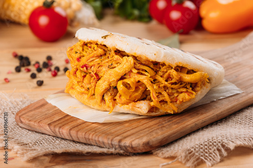 Delicious and provocative arepa with crushed chicken and around it some ingredients of its preparation