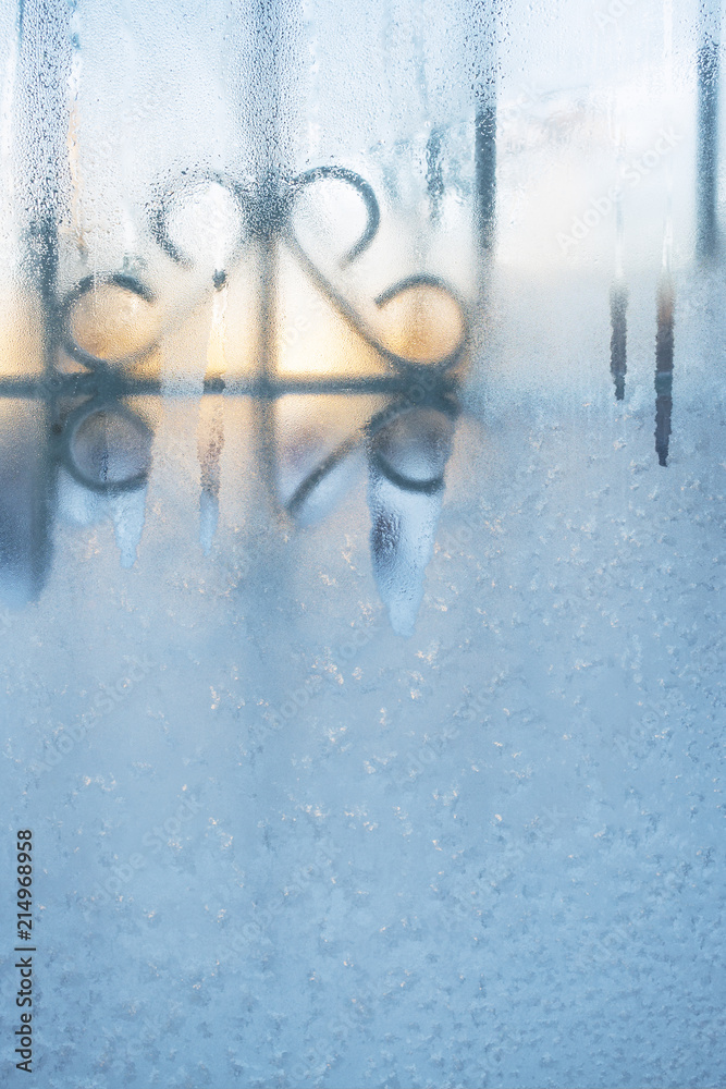 Fototapeta premium Frozen window with carved lattice slightly thawed from morning sun.