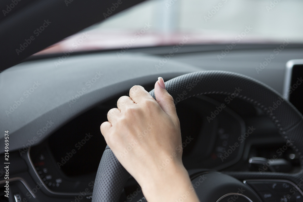 The hand of a girl with a stylish manicure lies on the handlebars in a saloon car.