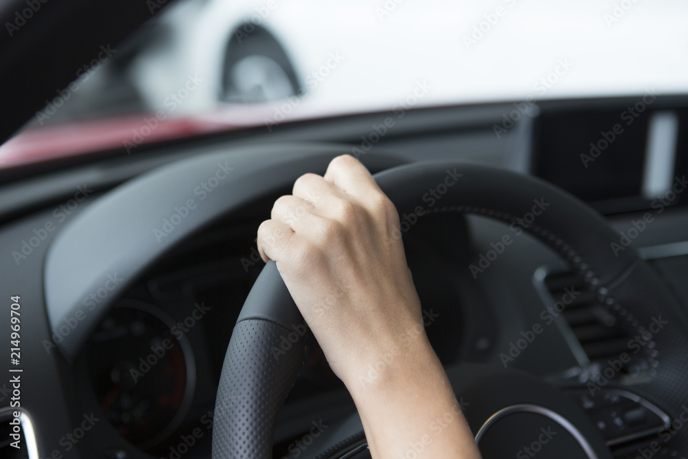 The hand of a girl with a stylish manicure lies on the handlebars in a saloon car.