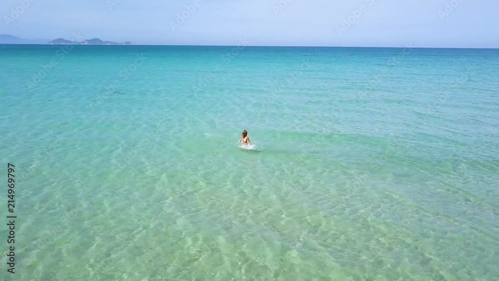 Happy woman enjoying sea water on summer beach drone view. Woman in turquoise sea water on paradise beach aerial view. Happy woman enjoying sea water on summer beach drone view. Woman in turquoise sea water on paradise beach aerial view.