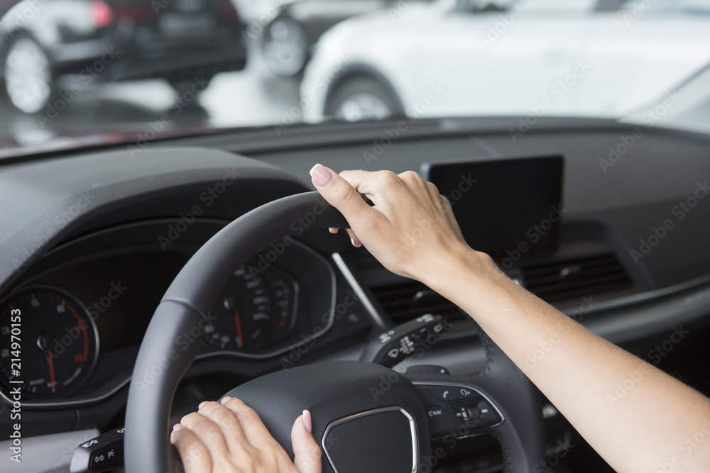 The hand of a girl with a stylish manicure lies on the handlebars in a saloon car.