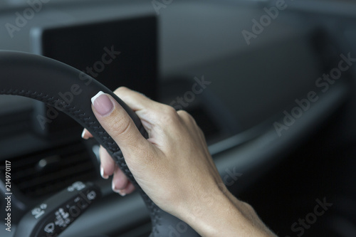 The hand of a girl with a stylish manicure lies on the handlebars in a saloon car.