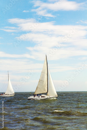 Sailboat Yachts at Sea on blue cloudy sky background.