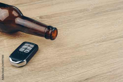 do not drink and drive concept, close up of a bottle of beer and a remote car key on wooden table