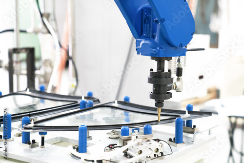 Industrial automated robot arm holding car glass in factory