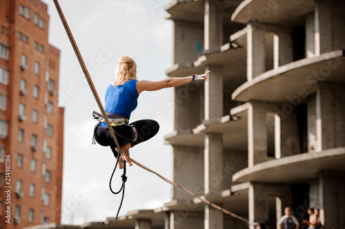 Rear view woman sitting on the two legs on the slackline rope