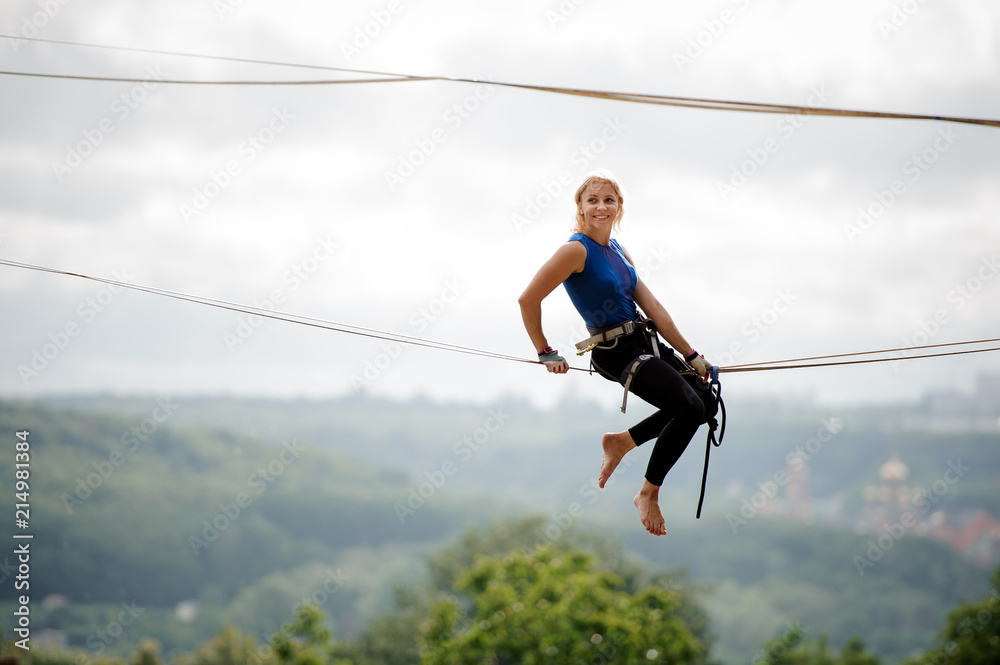 Side view smiling girl sitting on the slackline rope