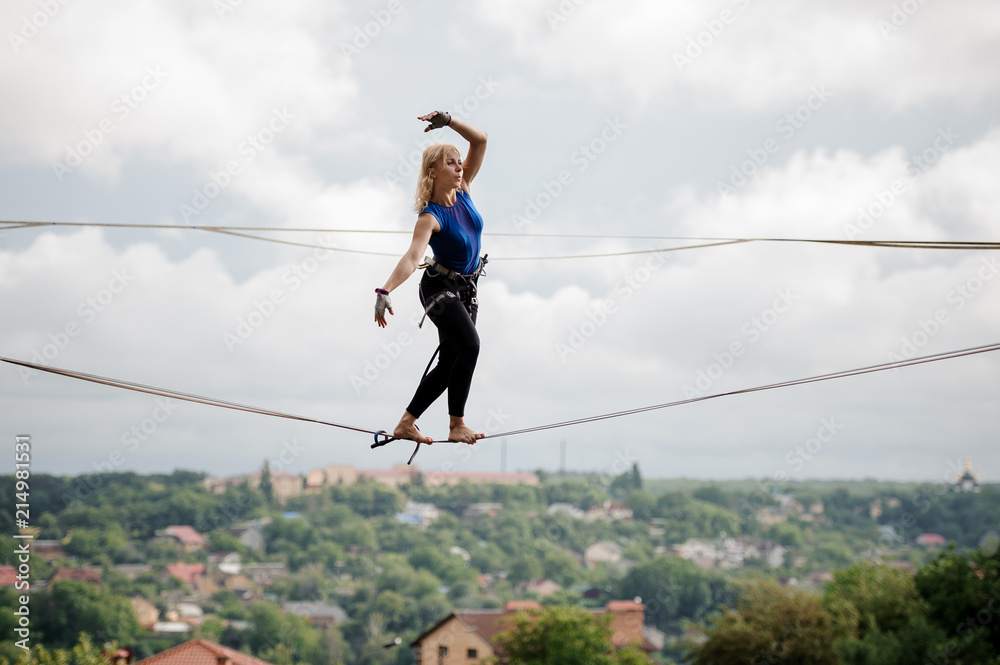 Young woman standing tilted her hands in the right direction on the slackline