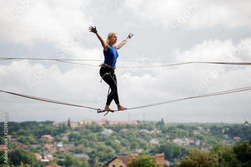 Young woman walking with arms raised on the slackline rope